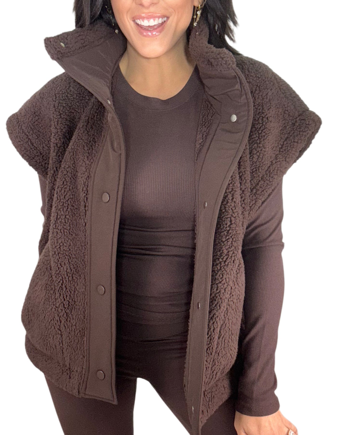 Woman wearing a brown fleece vest over a brown shirt on a white background