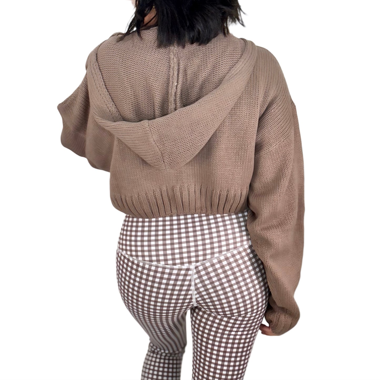 The back of a woman wearing a brown knit zip=up jacket and brown gingham pants on a white background