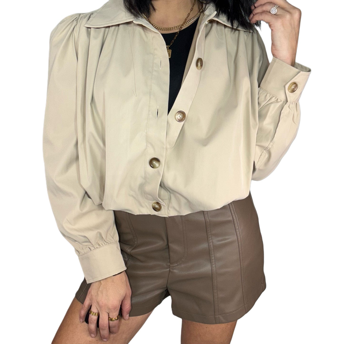 Woman wearing a beige jacket and brown leather shorts on a white background