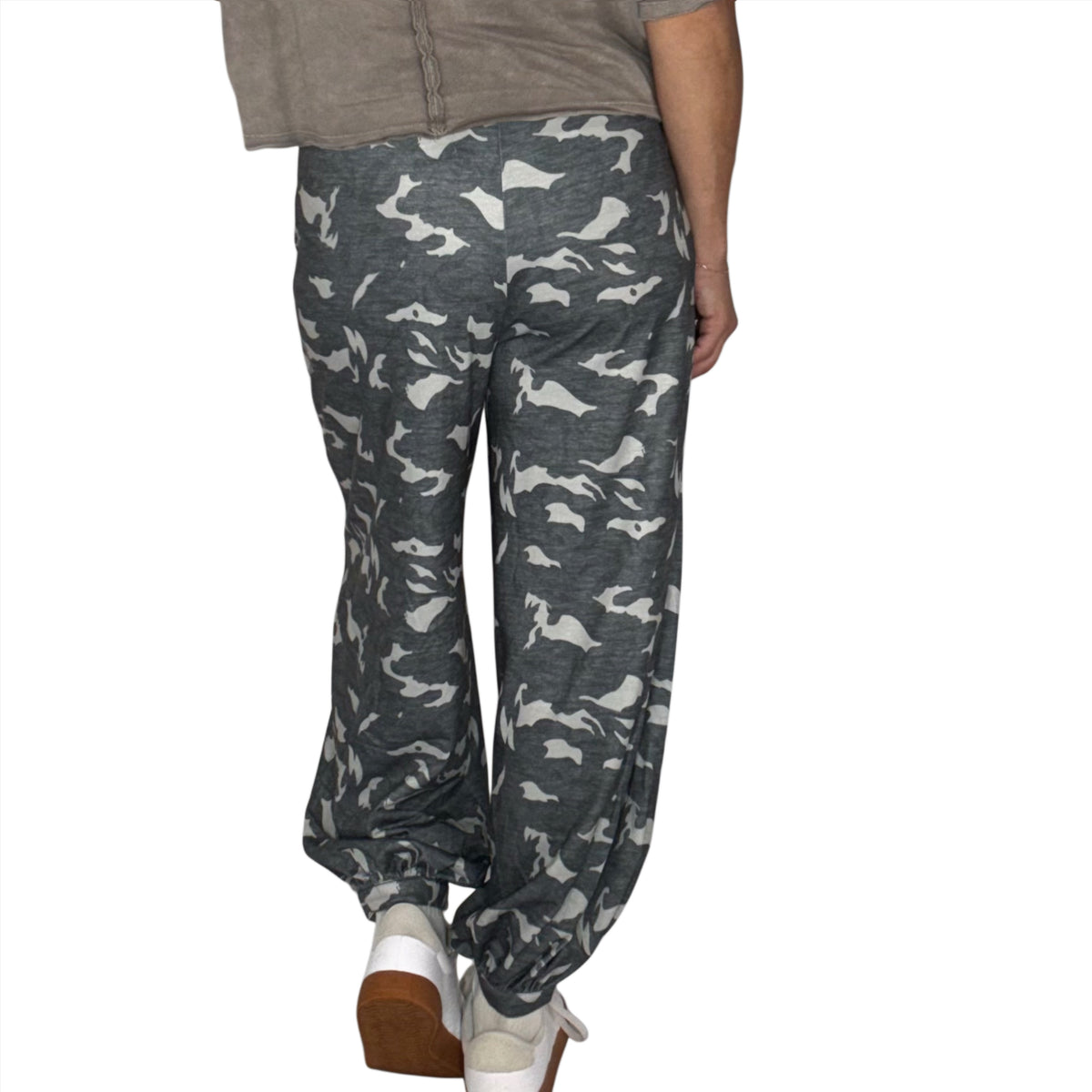 Back profile of a woman wearing loose fit lounge camouflage cargo pants with a brown tee, on a white background