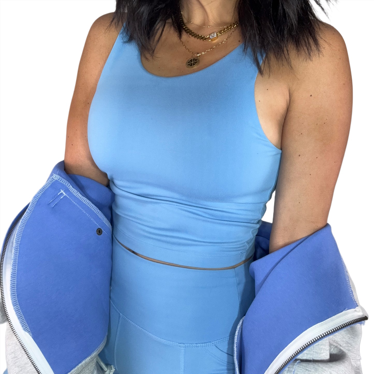 Side profile of a women wearing a powder blue tank top and leggings set on a white background