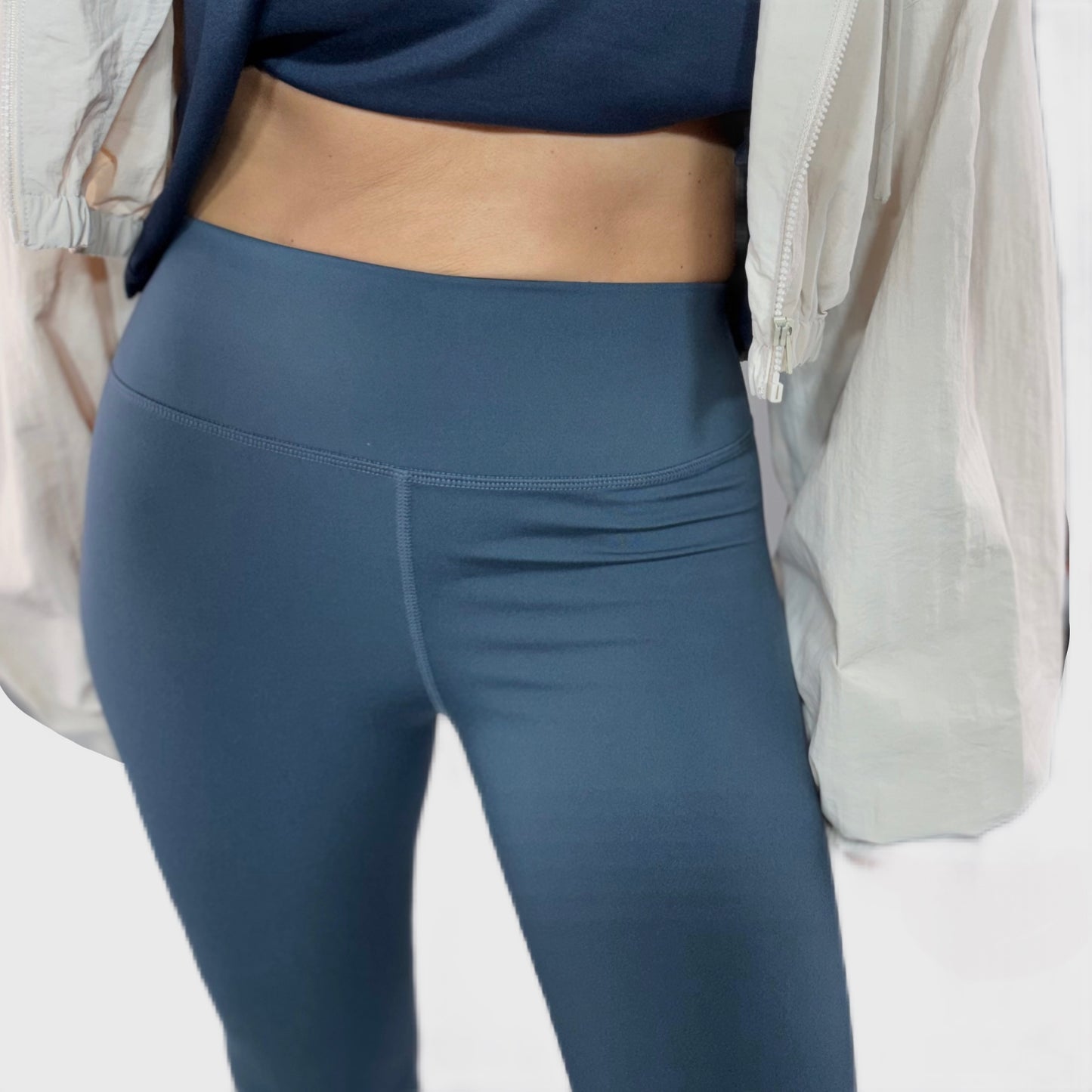 Woman wearing dark navy bootcut leggings with a dark navy top and a white background
