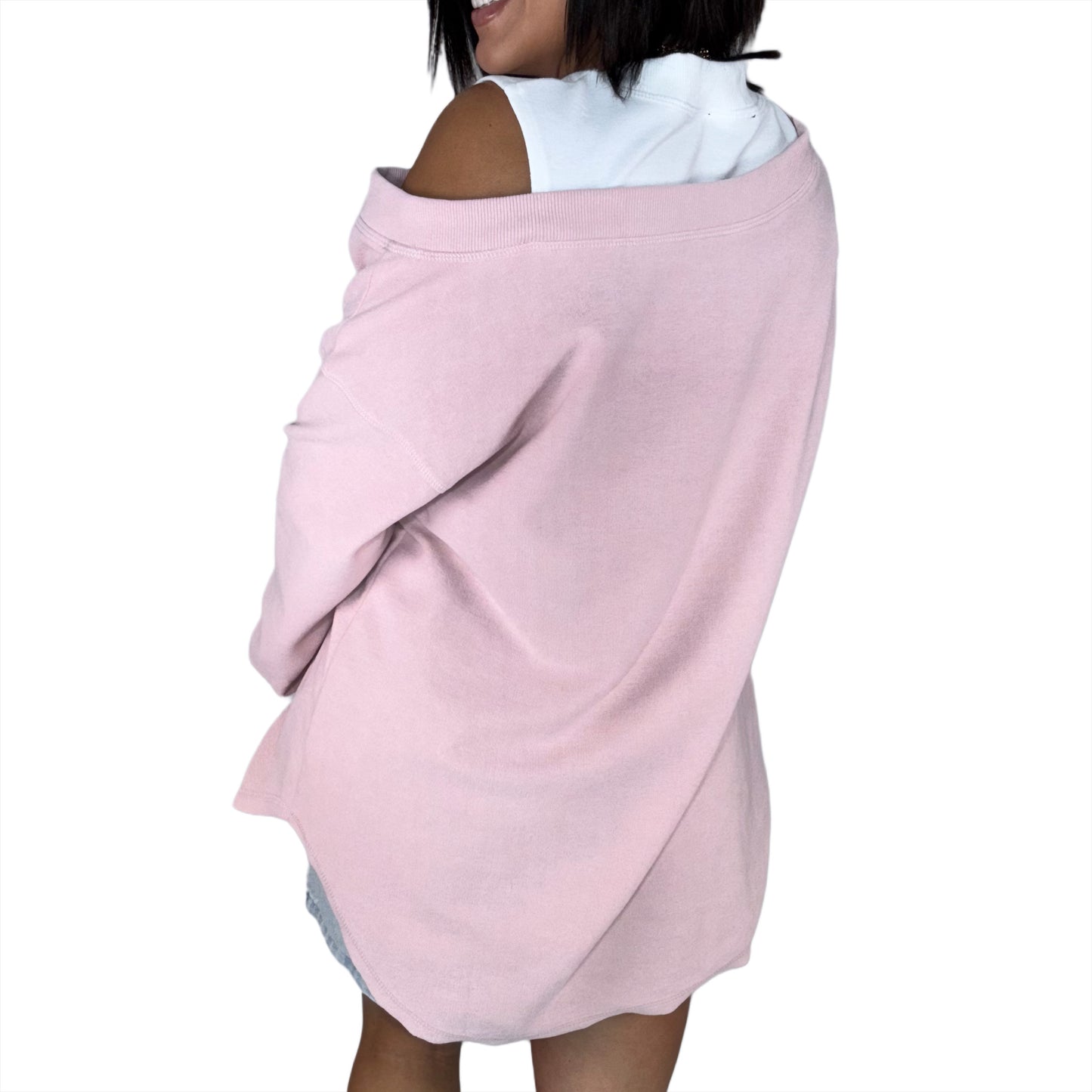 Woman wearing a light drop shoulder top, modeling the back on a white background