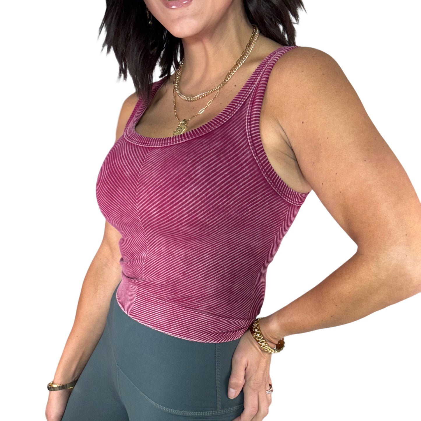 Woman wearing a maroon ribbed tank top and green leggings on a white background