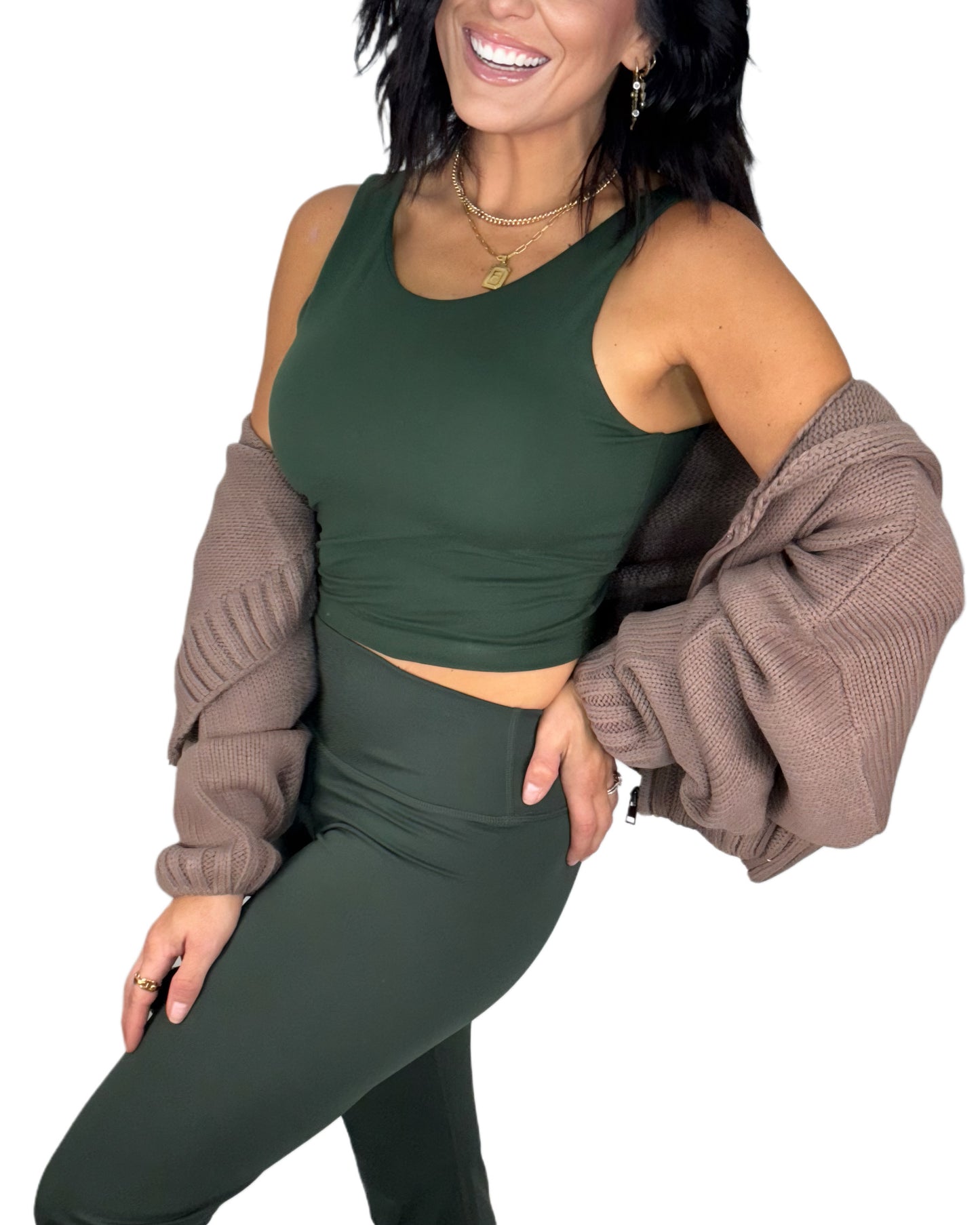 Woman side profile wearing a green athletic outfit with a brown knit jacket on a white background