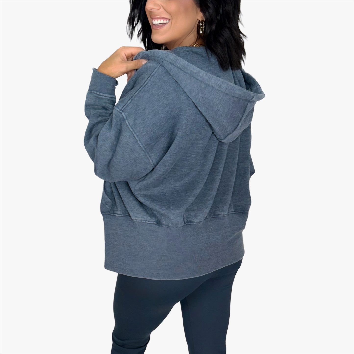 Woman wearing a navy hoodie turned around on a white background