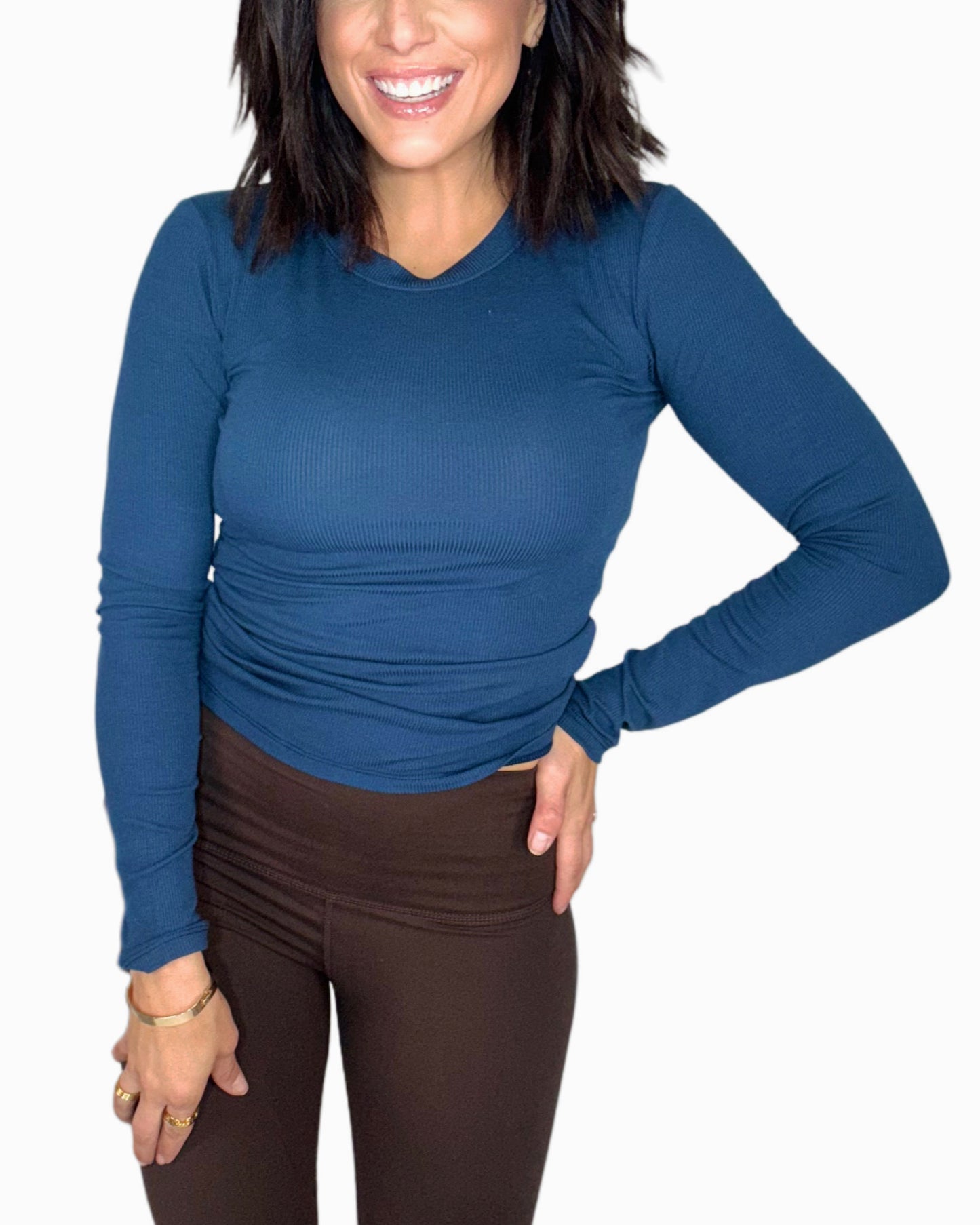 Woman wearing a blue long-sleeve top and brown pants on a white background