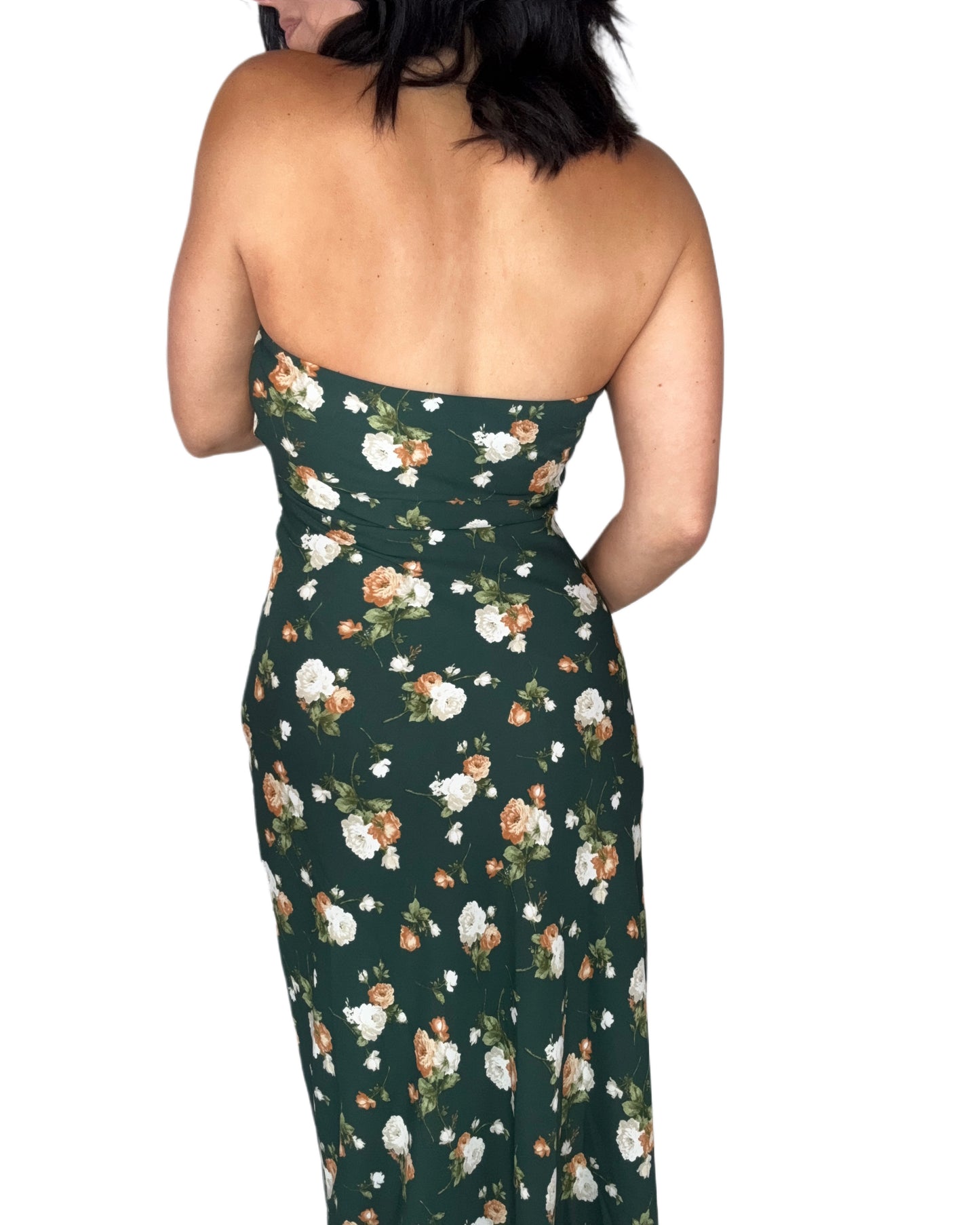 Back profile of a woman wearing a hunter green floral maxi dress on a white background