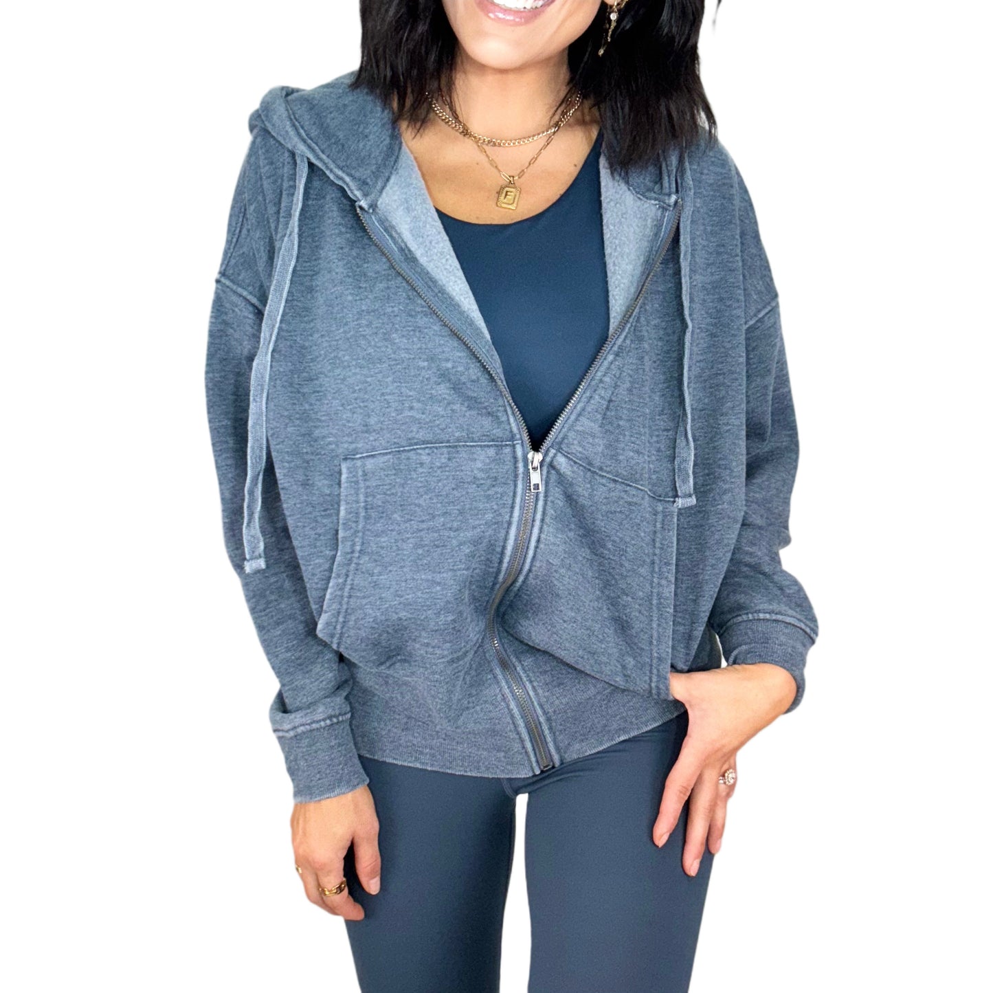 Woman wearing a navy zip-up hoodie and navy leggings on a white background
