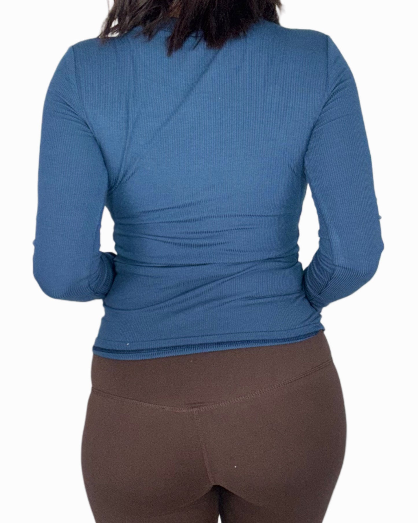 Blue long-sleeve top worn by a person on a white background