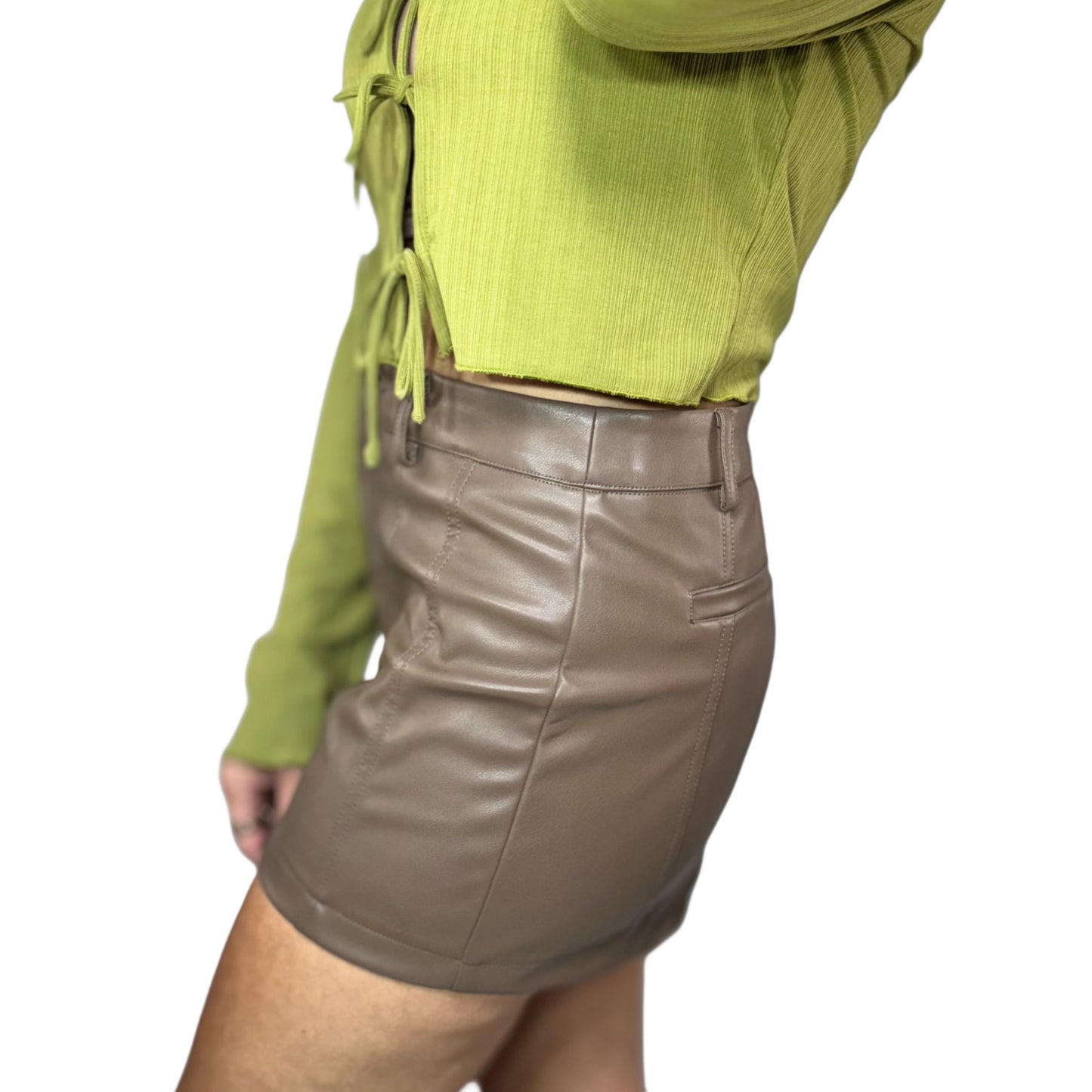 Woman wearing a green top and brown leather skirt on a white background