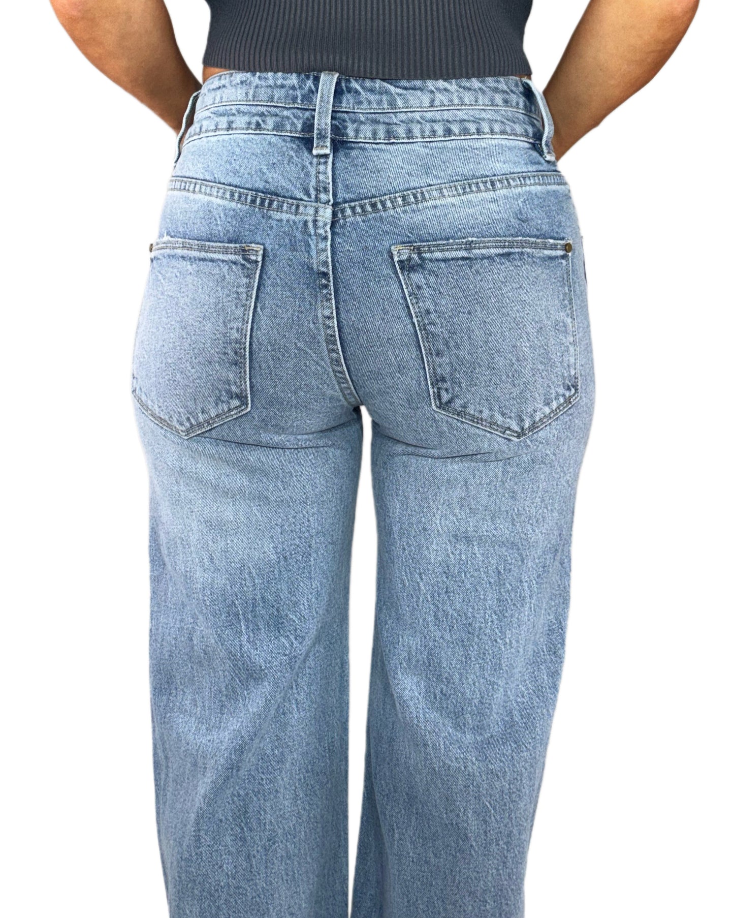 Back profile of a woman wearing light denim jeans on a white background