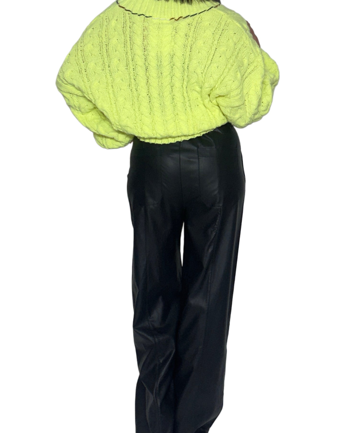 Back profile of a woman wearing a bright neon knitted sweater and black pants on a white background