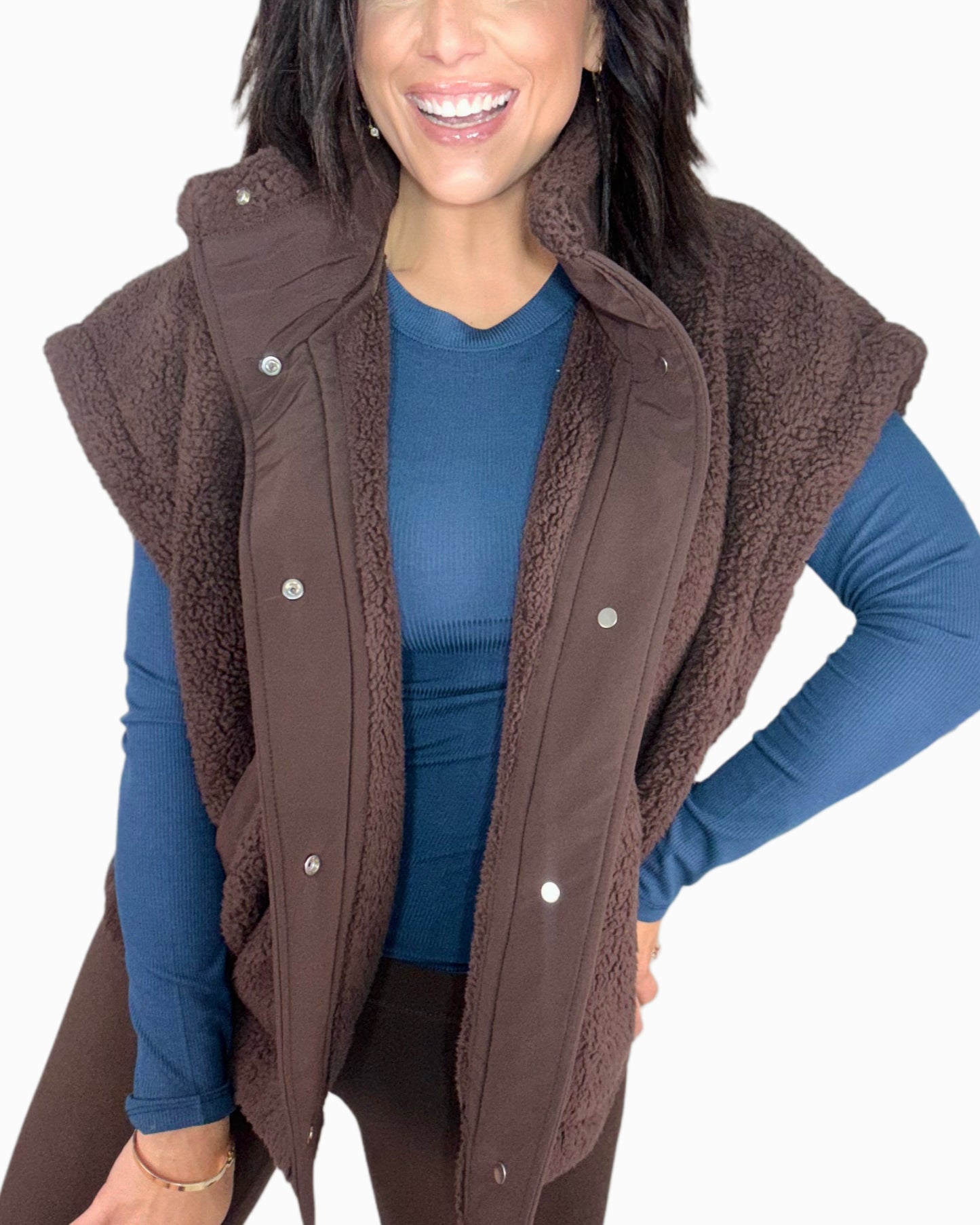 Woman wearing a brown vest over a blue shirt on a white background