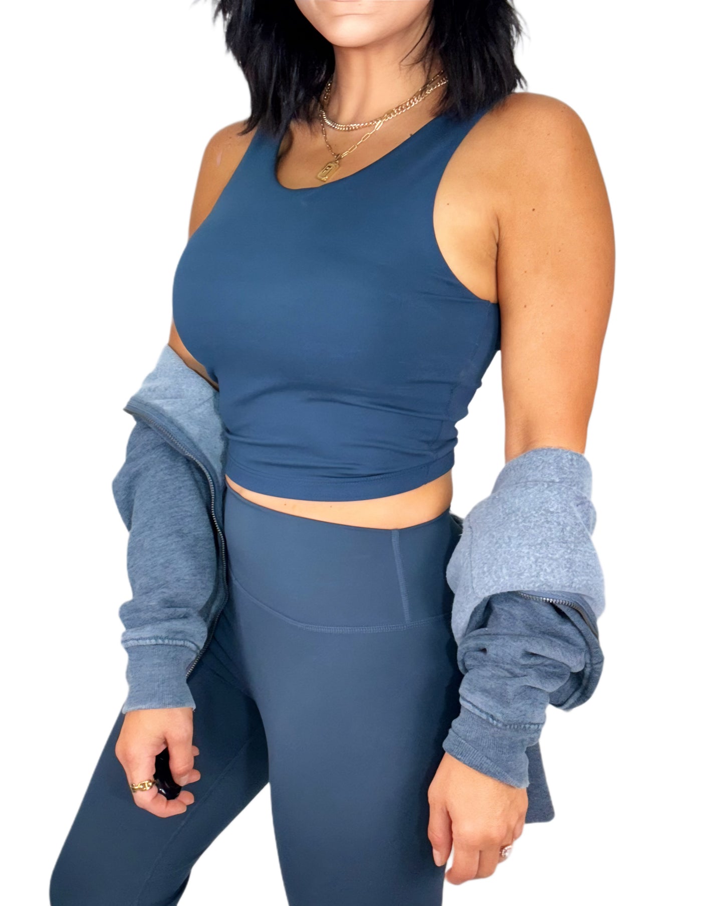 Side profile of a woman wearing a navy athletic set and a navy jacket on a white background