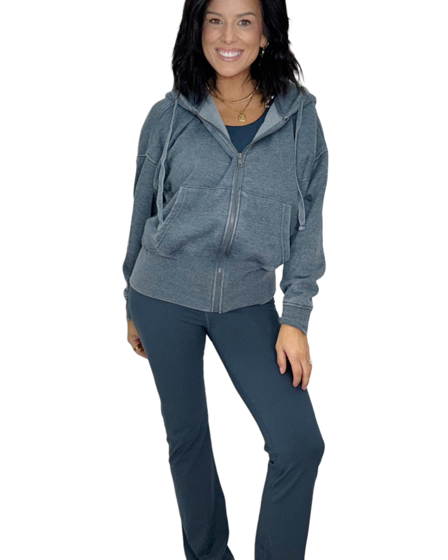 Woman wearing a navy hoodie zip up jacket and navy athletic pants on a white background