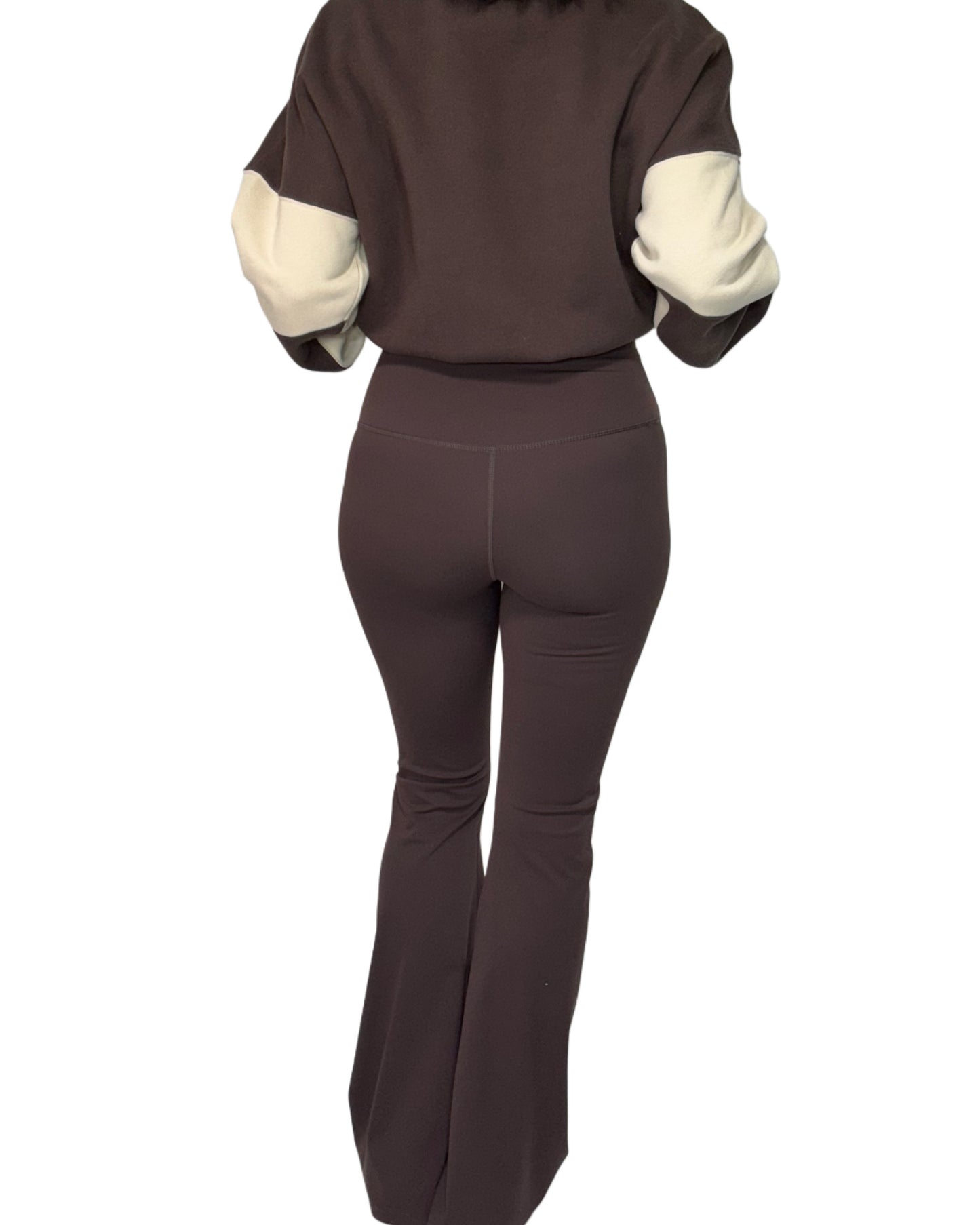 Back profile of woman wearing brown active flared pants and brown and cream blocked sweatshirt on a white background