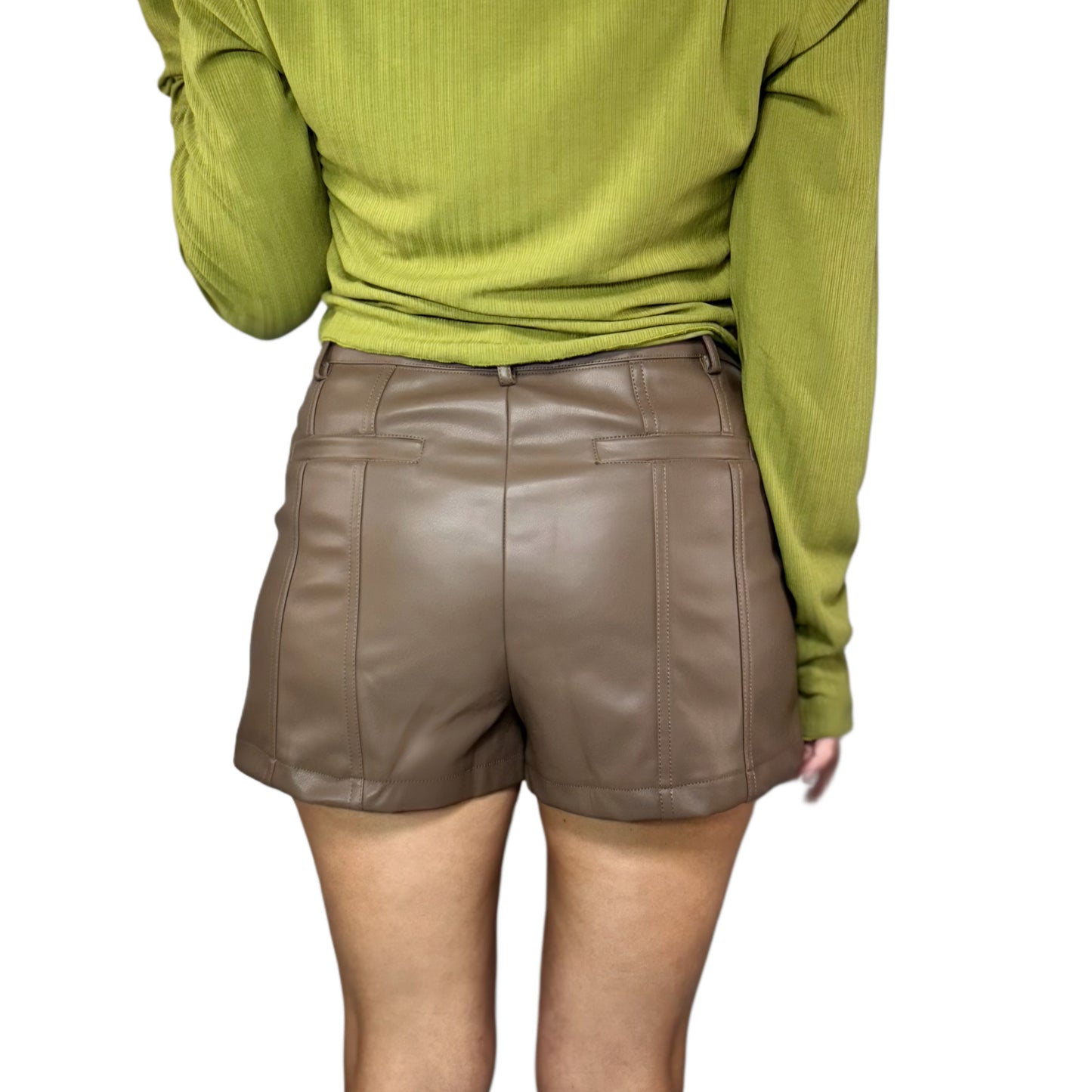 Woman wearing brown leather shorts and a green top on a white background