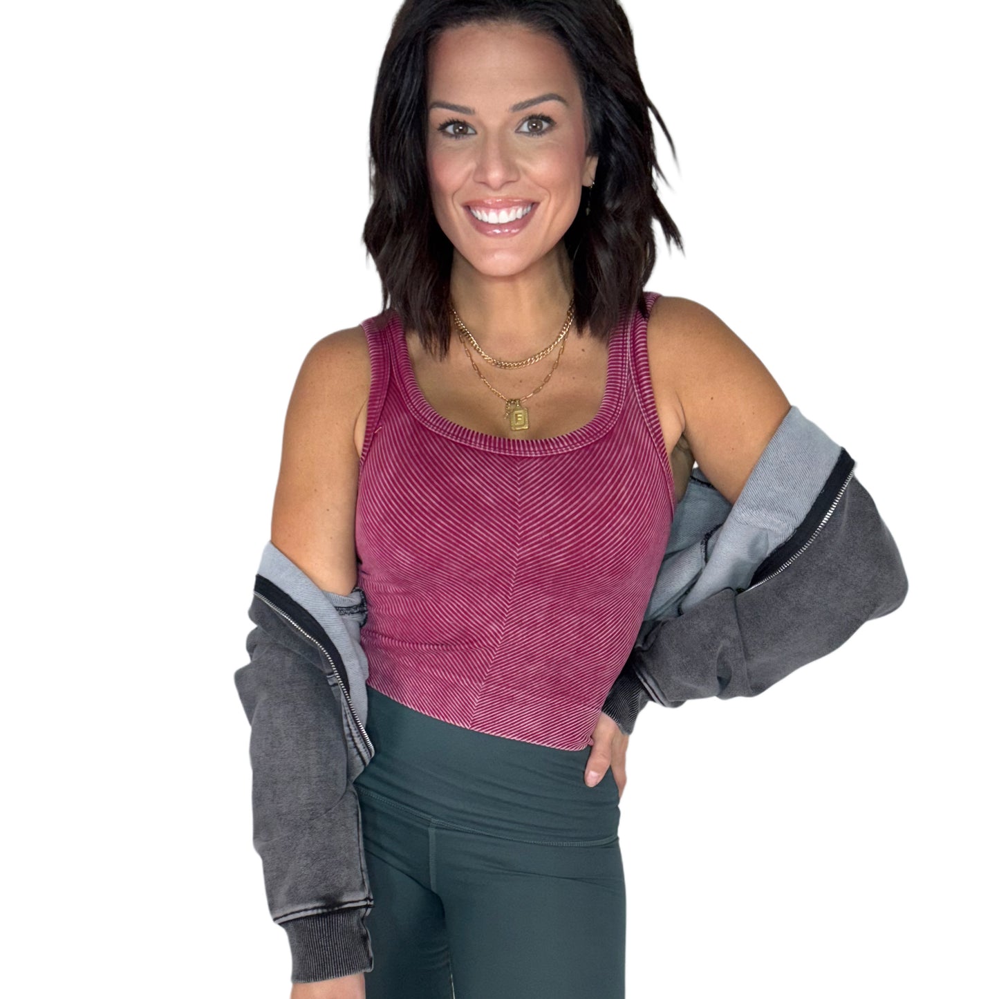 Woman wearing a maroon ribbed tank top and gray acid washed jacket on a white background