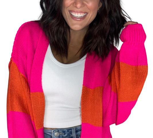 Close up of a woman wearing a pink and red cardigan with a white tank, on a white background