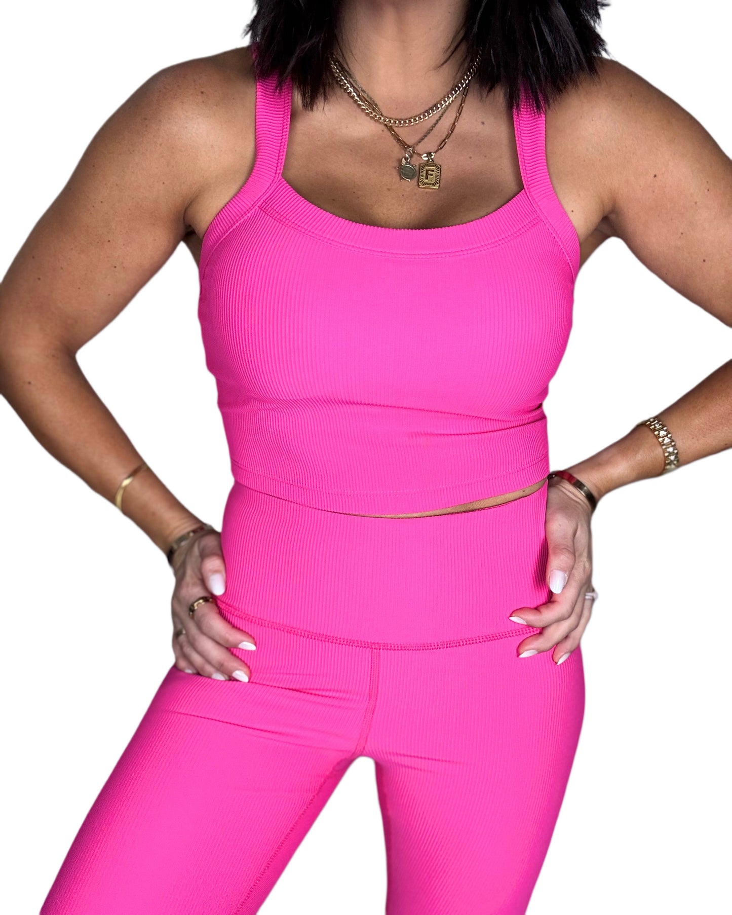 Close up of a woman wearing a pink athletic ribbed outfit on a white background