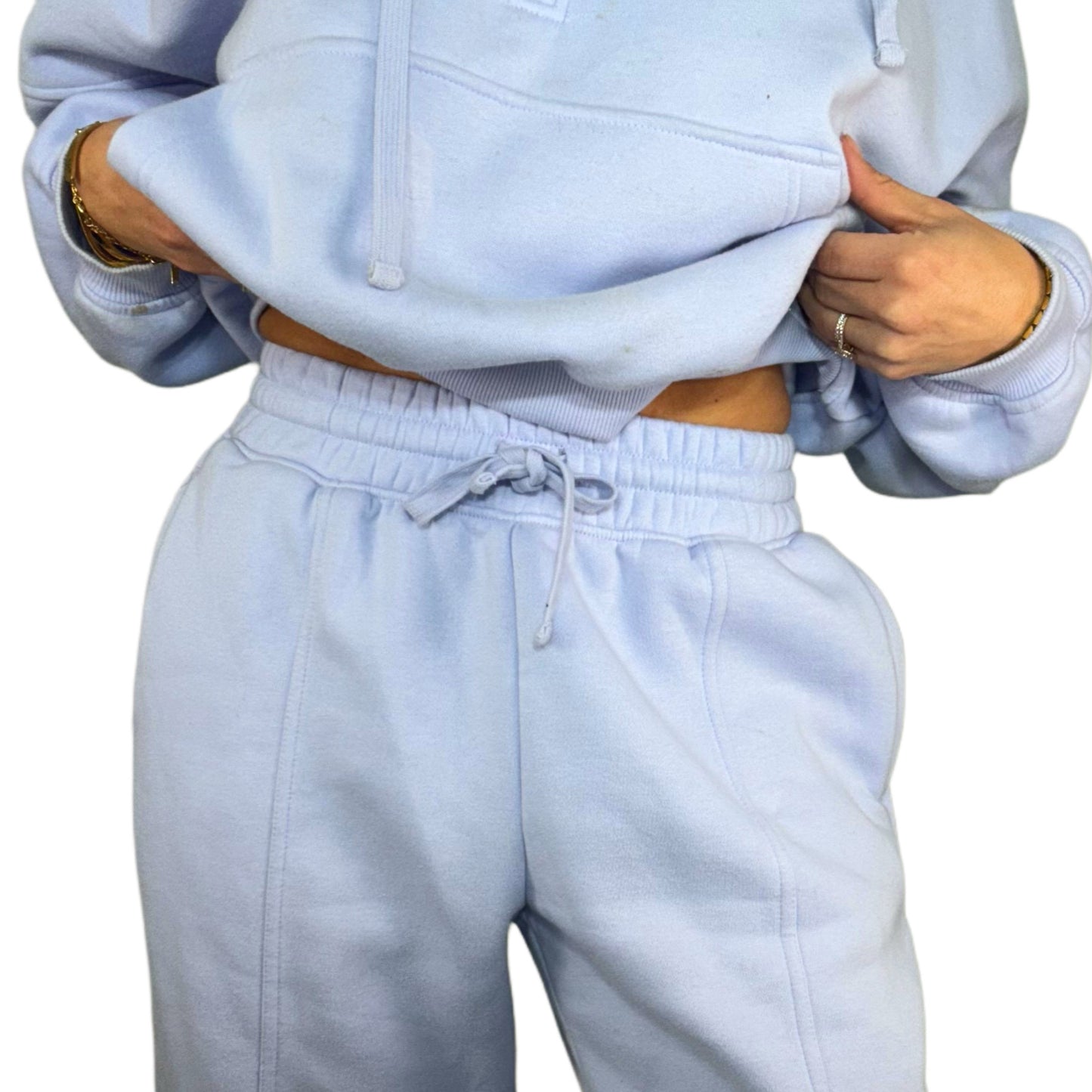 Close up of a woman wearing a light blue hoodie and pants set on a white background