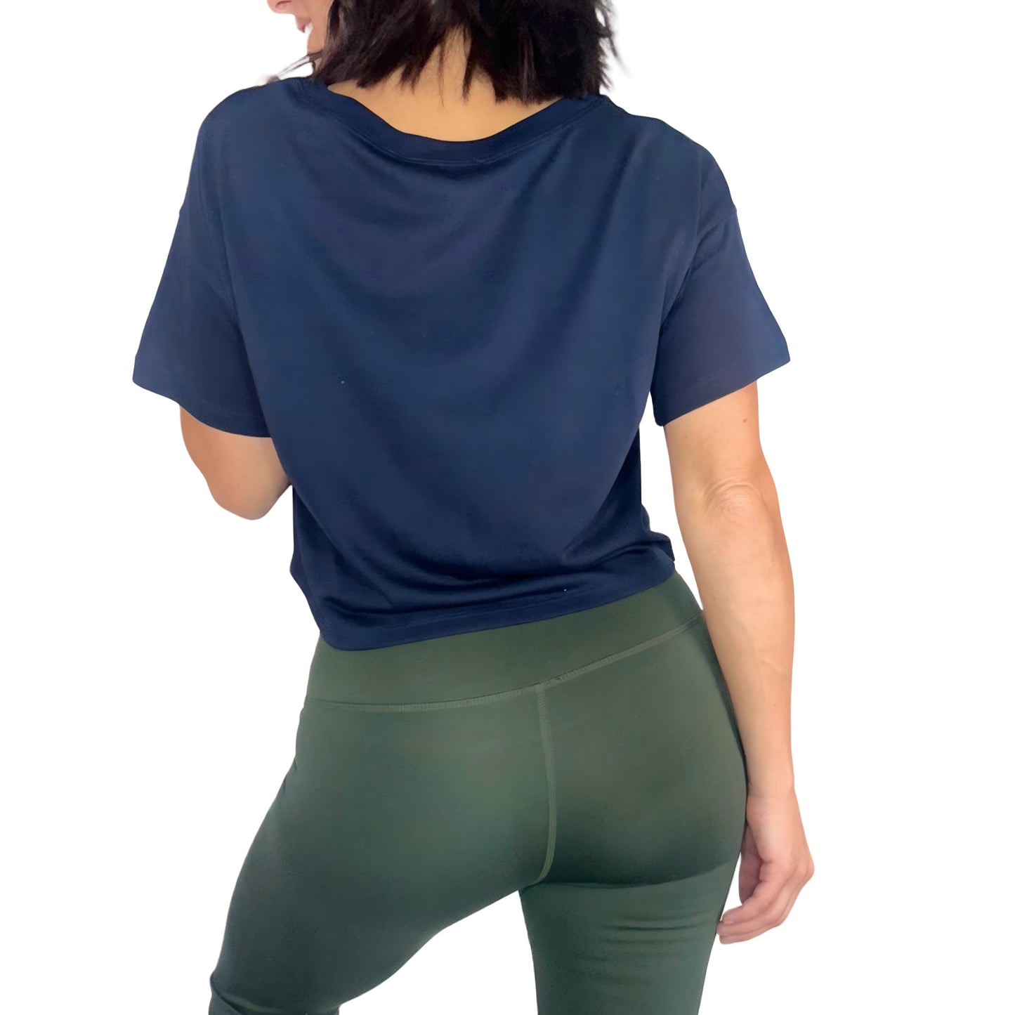 Woman turned around wearing a navy cropped tee and green active pants on a white background