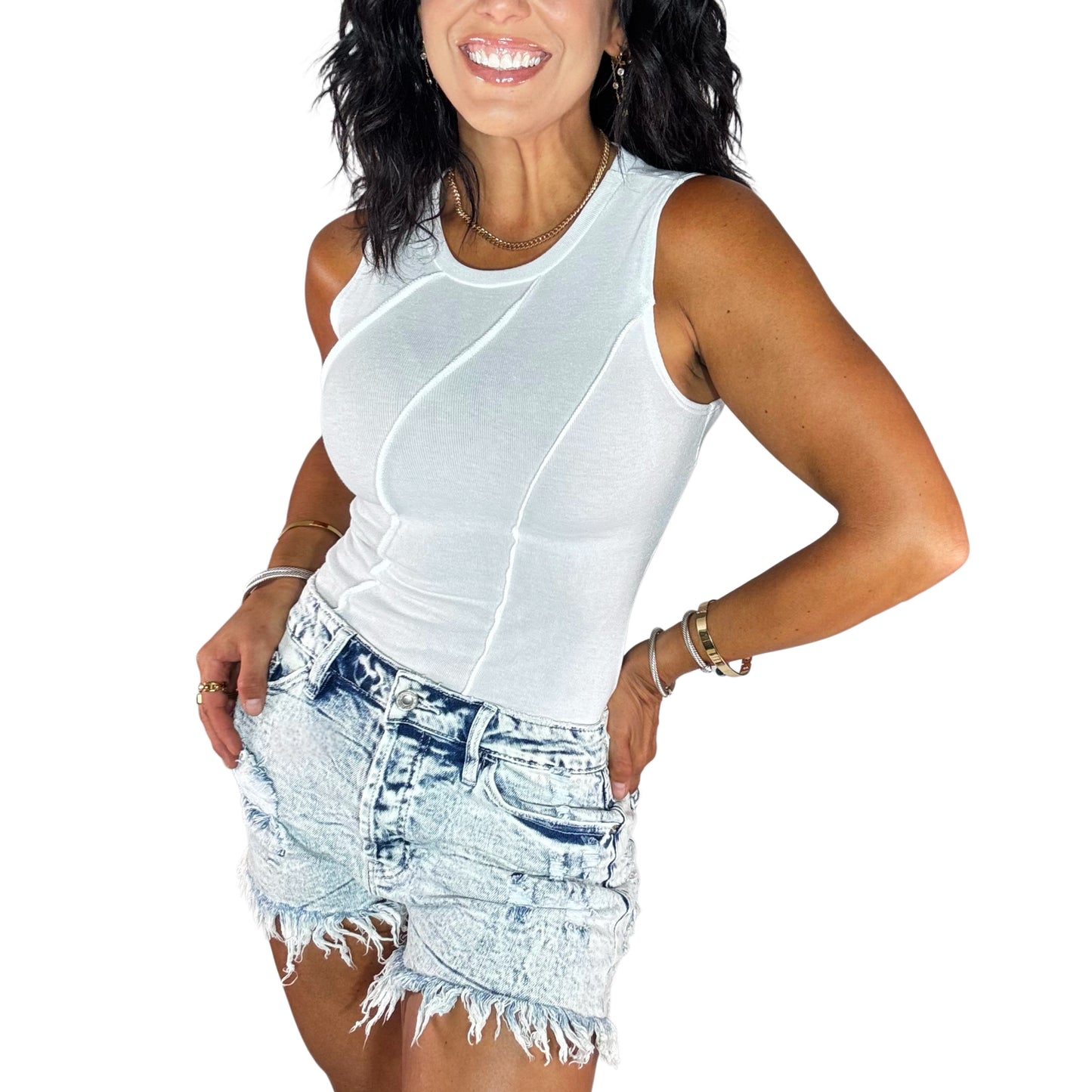 Side profile of a woman wearing a white sleeveless bodysuit with acid washed ribbed shorts on a white background