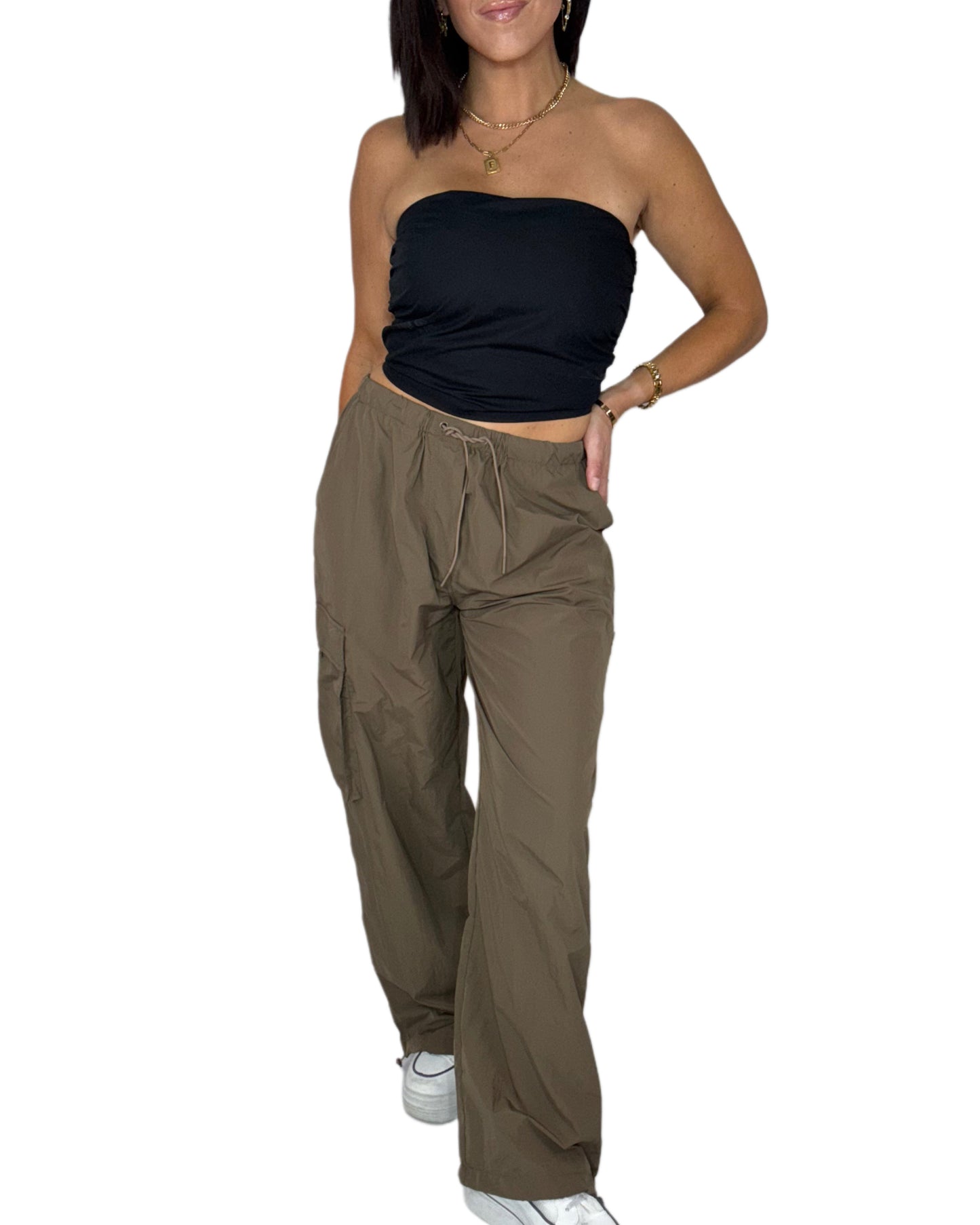 Woman wearing a black strapless top and brown wide-leg pants on a white background