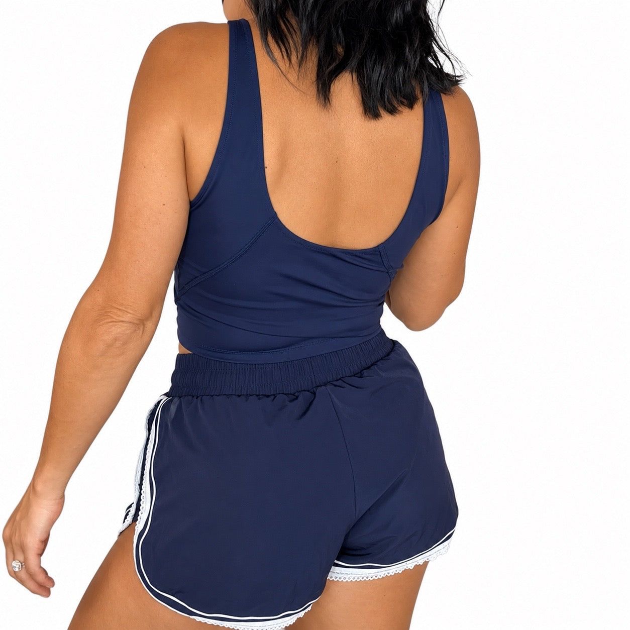 Back profile of a woman wearing a navy active tank and matching shorts on a white background