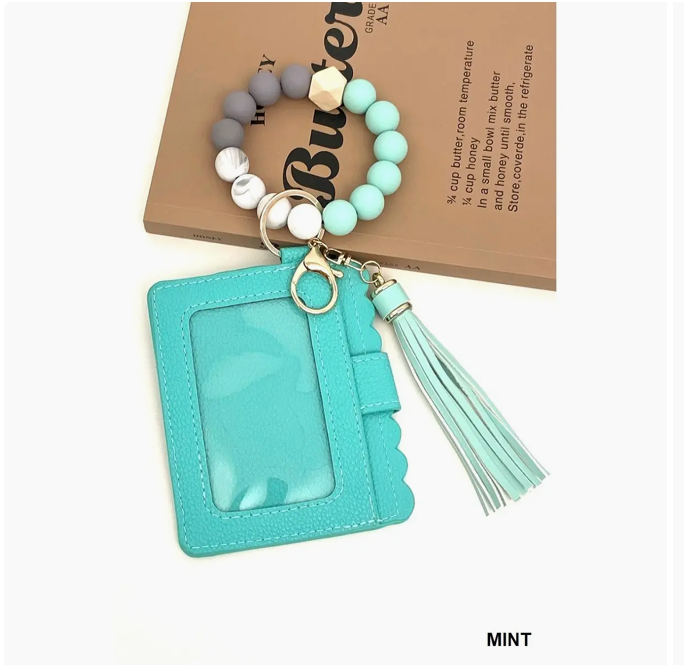 Mint green keychain with tassel and beaded bracelet on a beige background