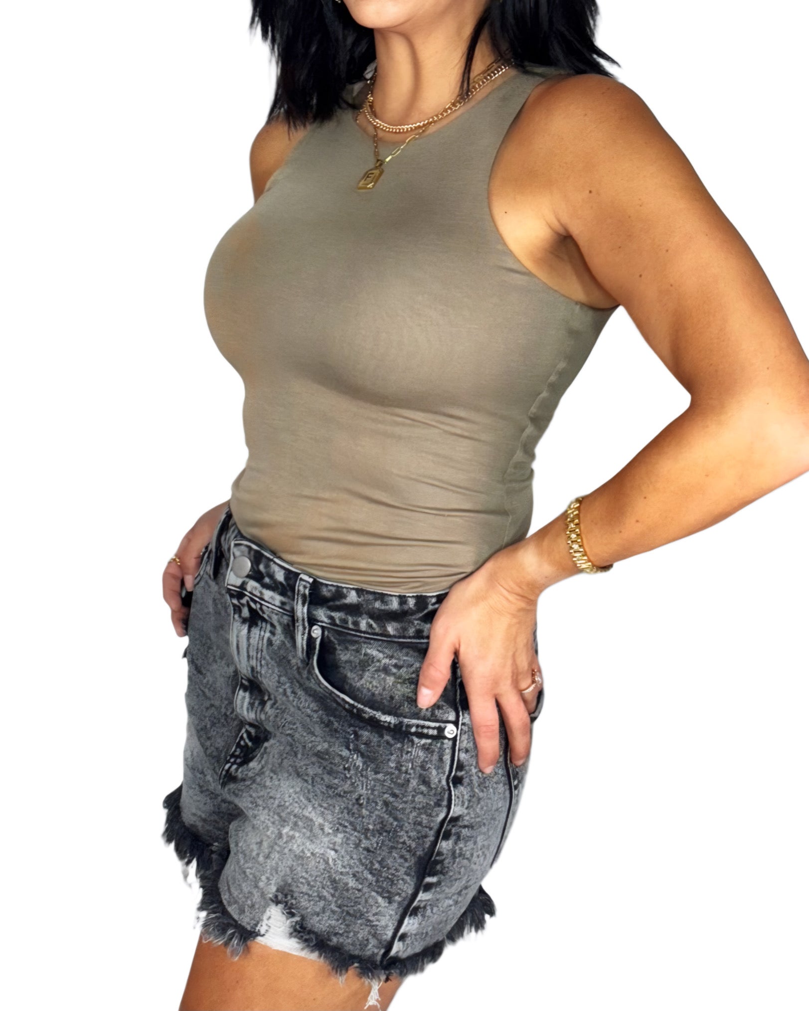Side profile of a woman wearing a mocha bodysuit with dark jean shorts and a white background