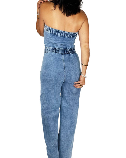 Back profile of a woman wearing a jean jumpsuit on a white background