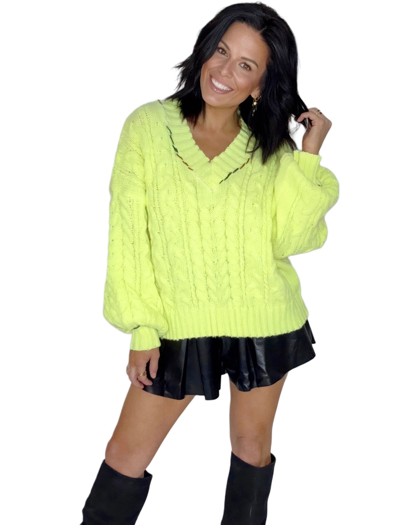 Woman wearing a bright neon sweater and black leather shorts on a white background