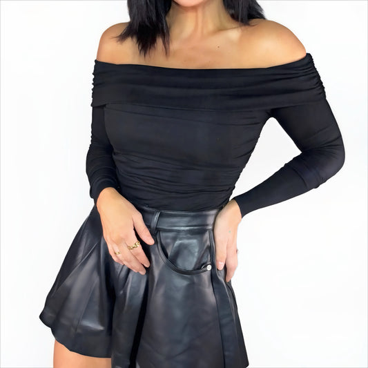 Black off-shoulder bodysuit and leather shorts on a white background