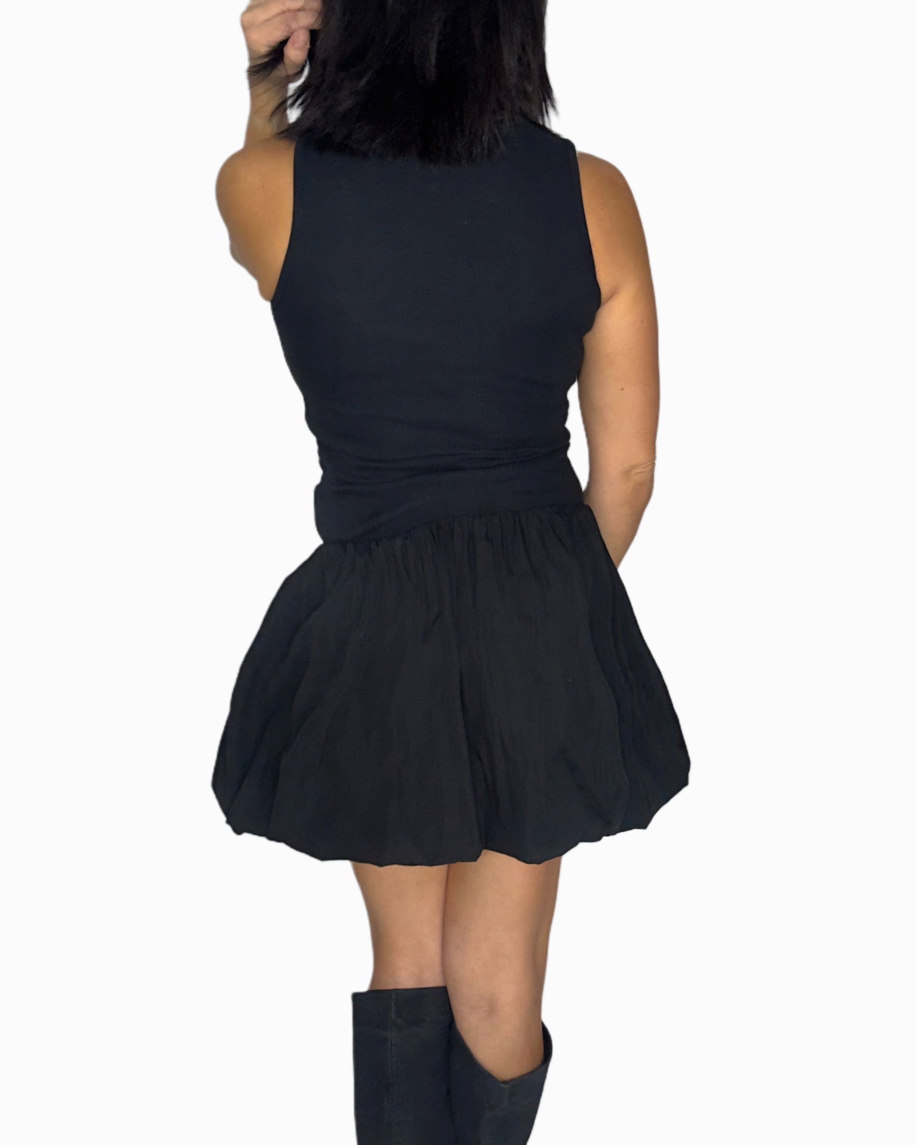 Back profile of a woman wearing a sleeveless dress worn by a person on a white background