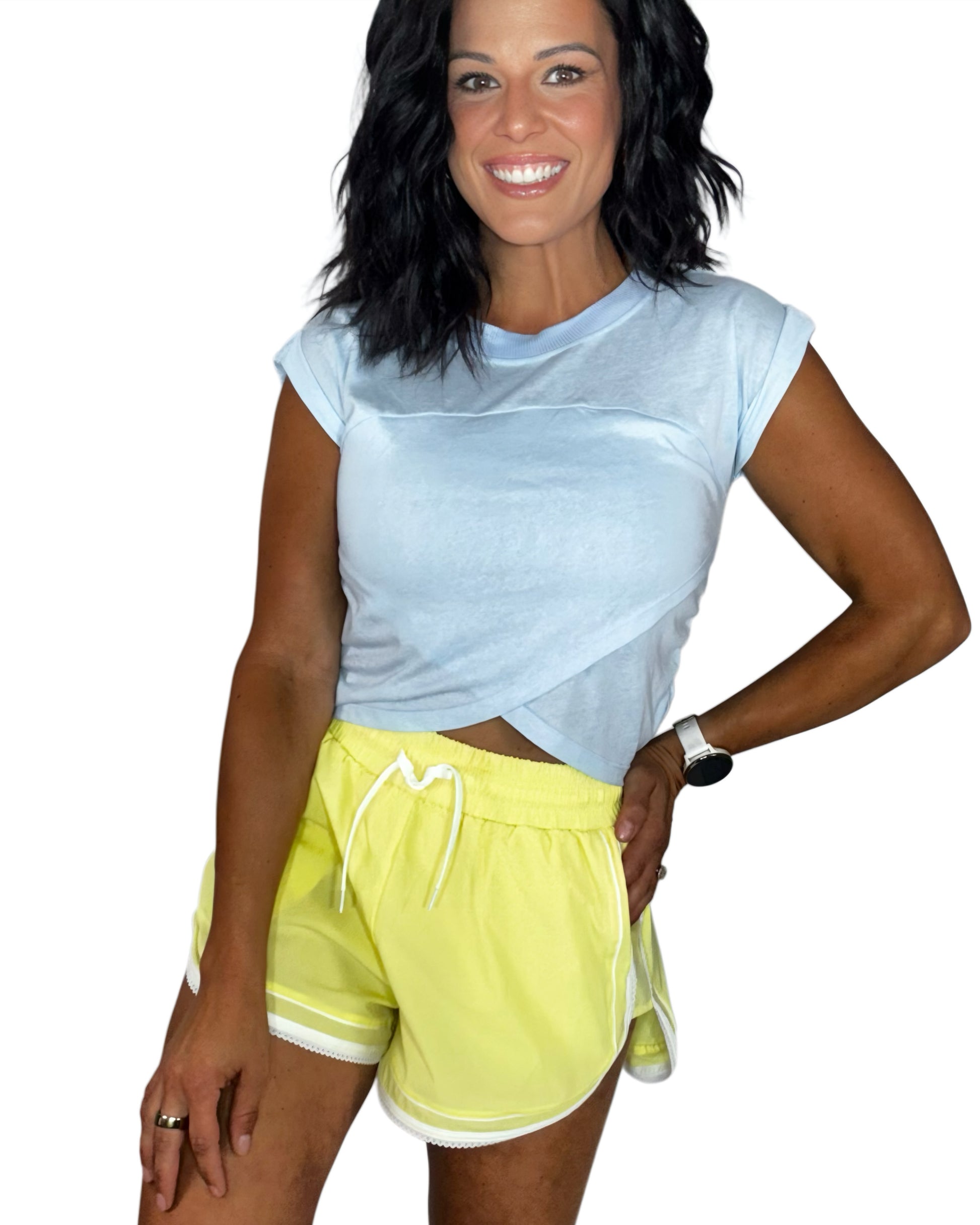 Woman wearing a light blue active cotton top with active yellow shorts, trimmed with lace on a white background 