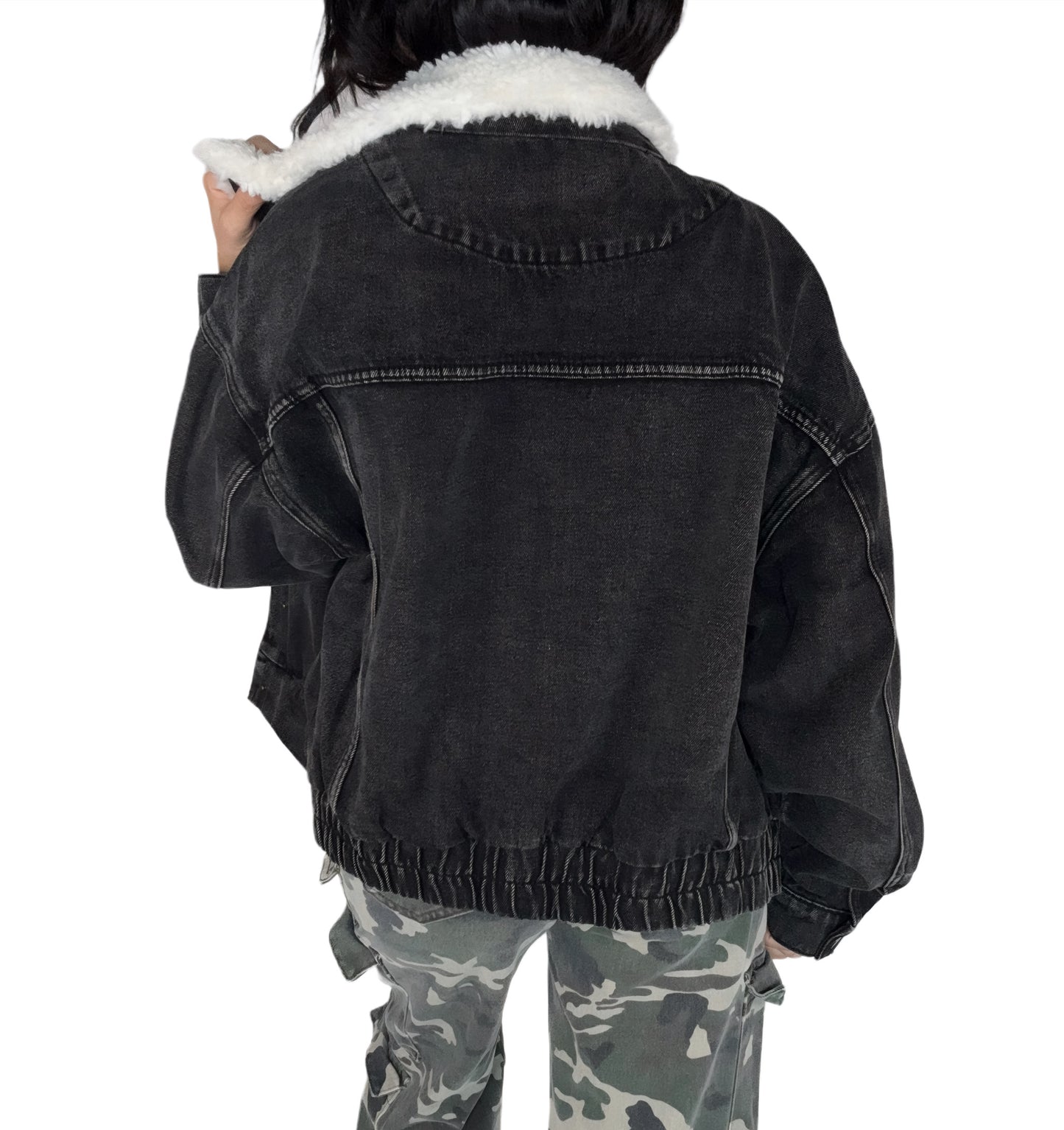 Back profile of a black denim jacket with white fur lining worn by a person, on a white background
