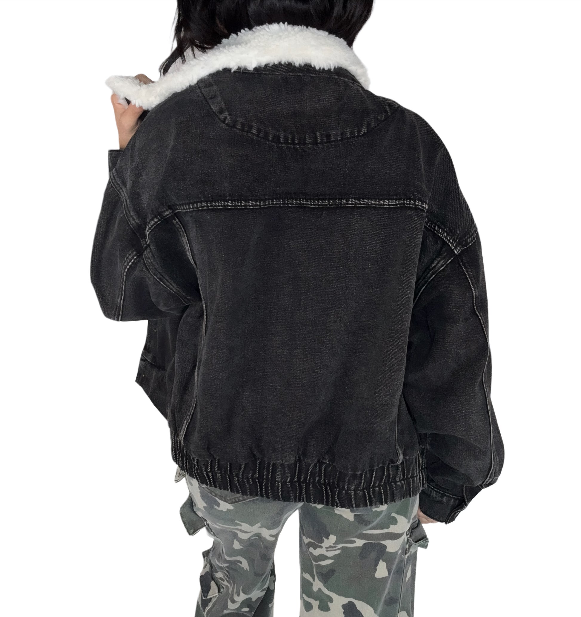 Back profile of a black denim jacket with white fur lining worn by a person, on a white background