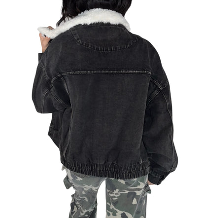 Back profile of a black denim jacket with white fur lining worn by a person, on a white background