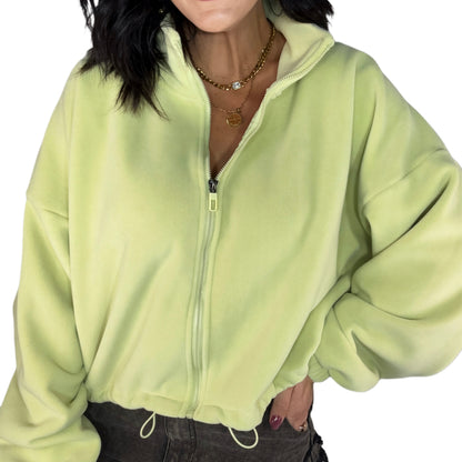 Person wearing a light green zip-up fleece on a white background