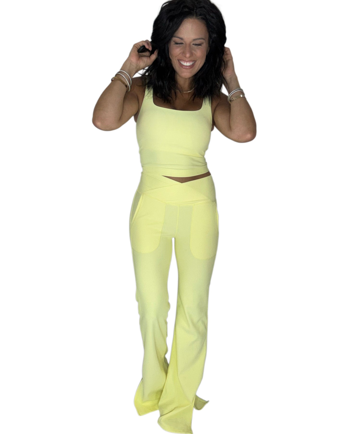 Woman wearing a ribbed yellow active pant set on a white background