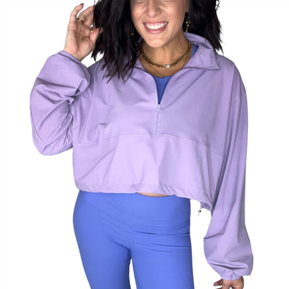Woman wearing a purple half-zip jacket and blue leggings on a white background