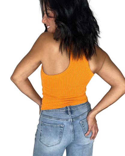 Back profile of a woman wearing a ribbed Y cut  orange tank top with medium washed jeans on a white background
