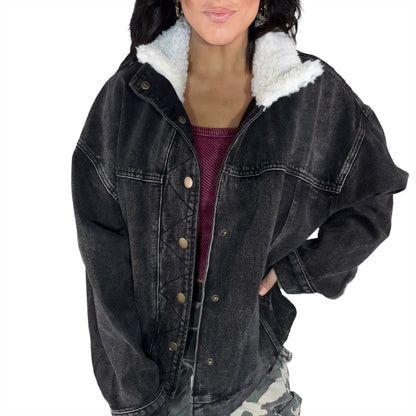 Black denim jacket with white fur lining worn by a woman on a white background