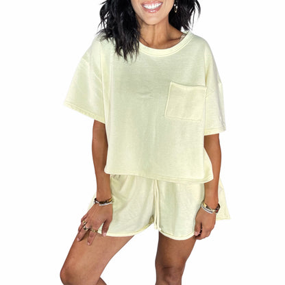Close up of a woman wearing a pale yellow short set, on a white background