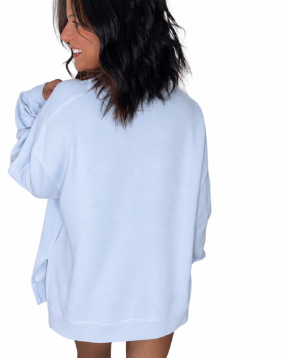Back profile of a woman wearing a light blue sweatshirt on a white background 