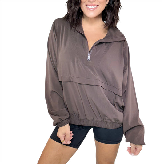 Woman wearing a brown ribbed pullover with a zipper on a white background