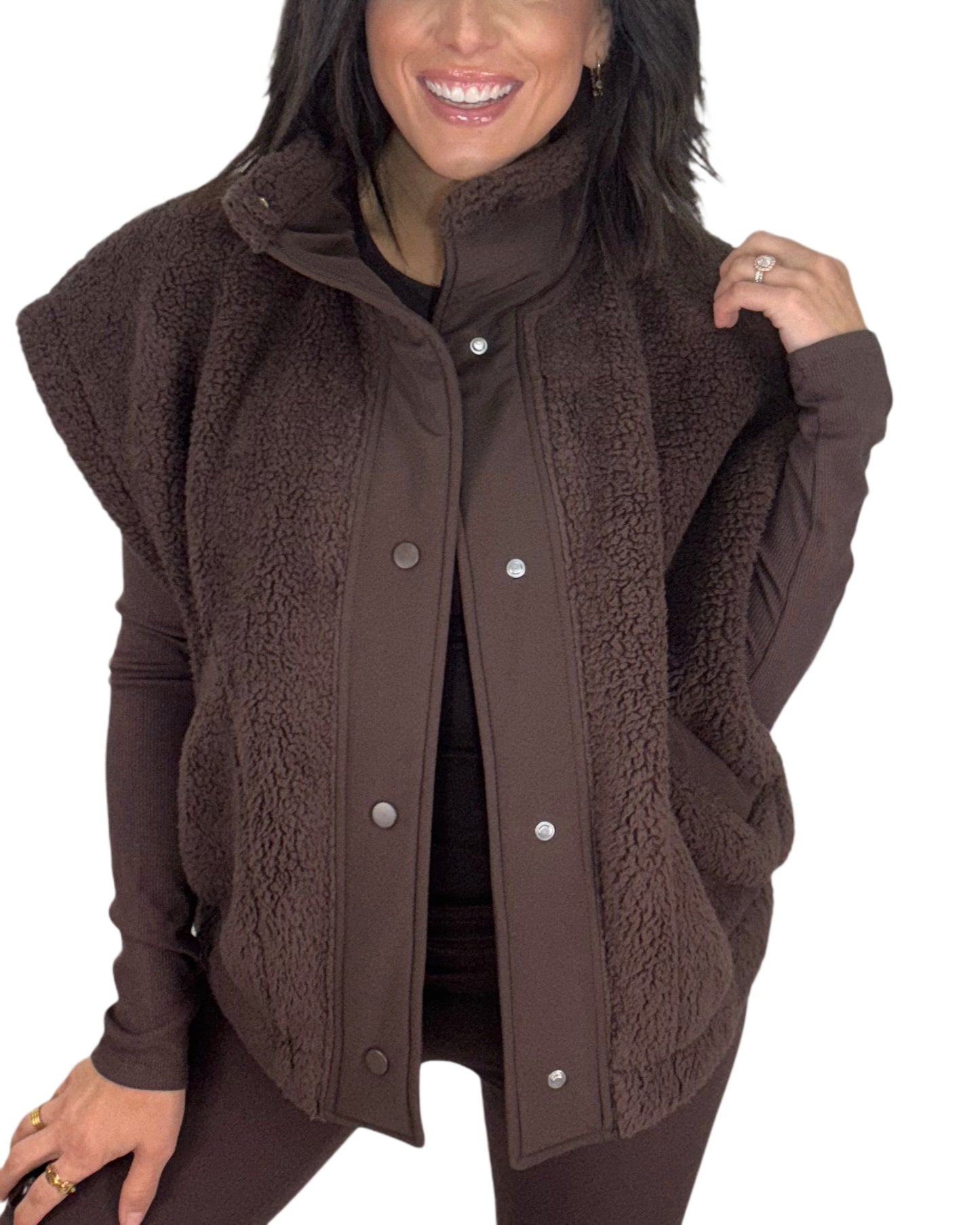 Close up of a woman wearing a brown fleece vest on a white background