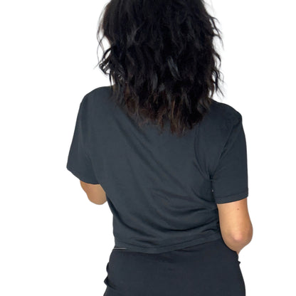 A person shown from the back wearing a black short-sleeve t-shirt and black bottoms, against a plain white background.